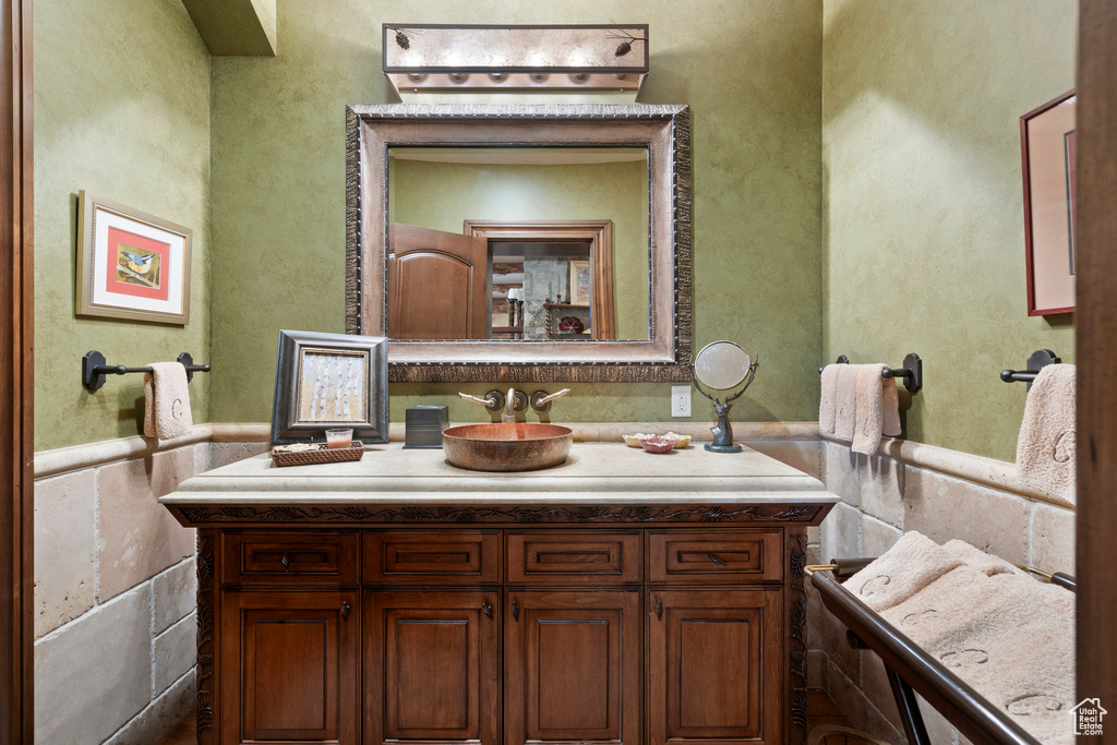 Bathroom with vanity, wainscoting, and tile walls