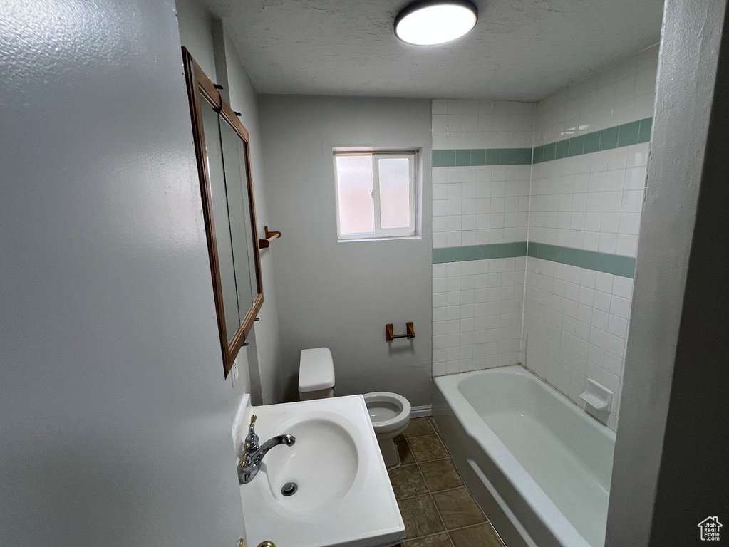 Bathroom with tile patterned floors, a textured ceiling, tub / shower combination, and vanity