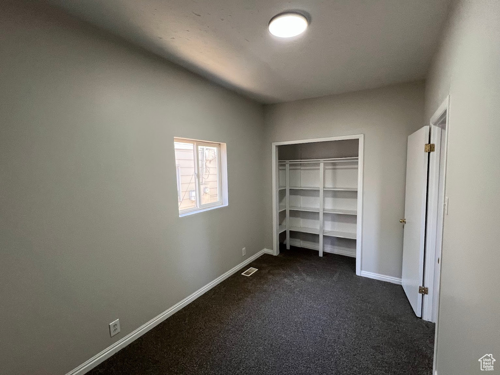 Unfurnished bedroom with dark carpet and a closet