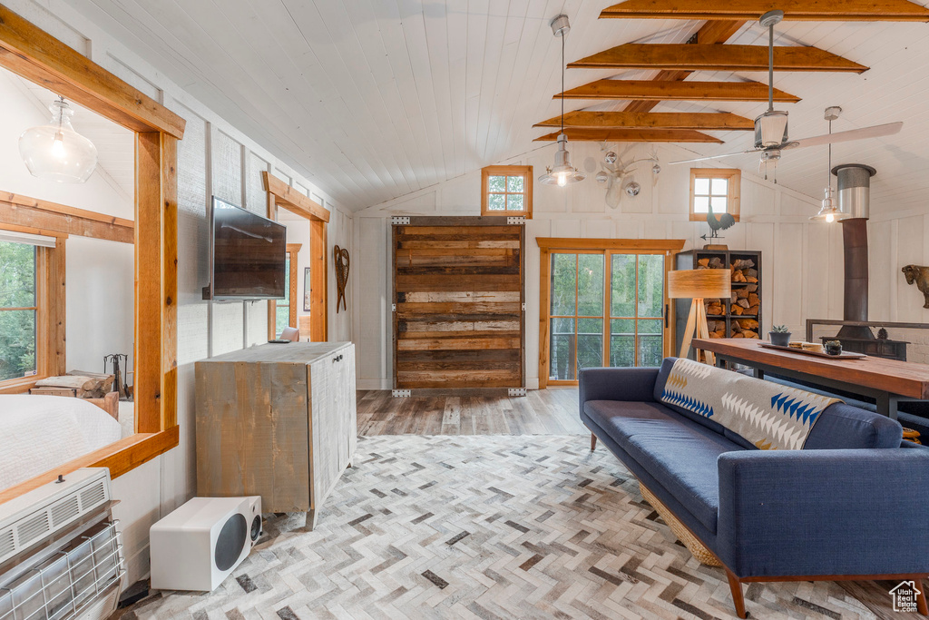 Living room with a ceiling fan, plenty of natural light, wood finished floors, high vaulted ceiling, and beamed ceiling