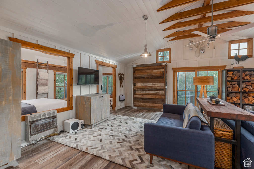 Living room featuring a ceiling fan, wood finished floors, heating unit, plenty of natural light, and high vaulted ceiling