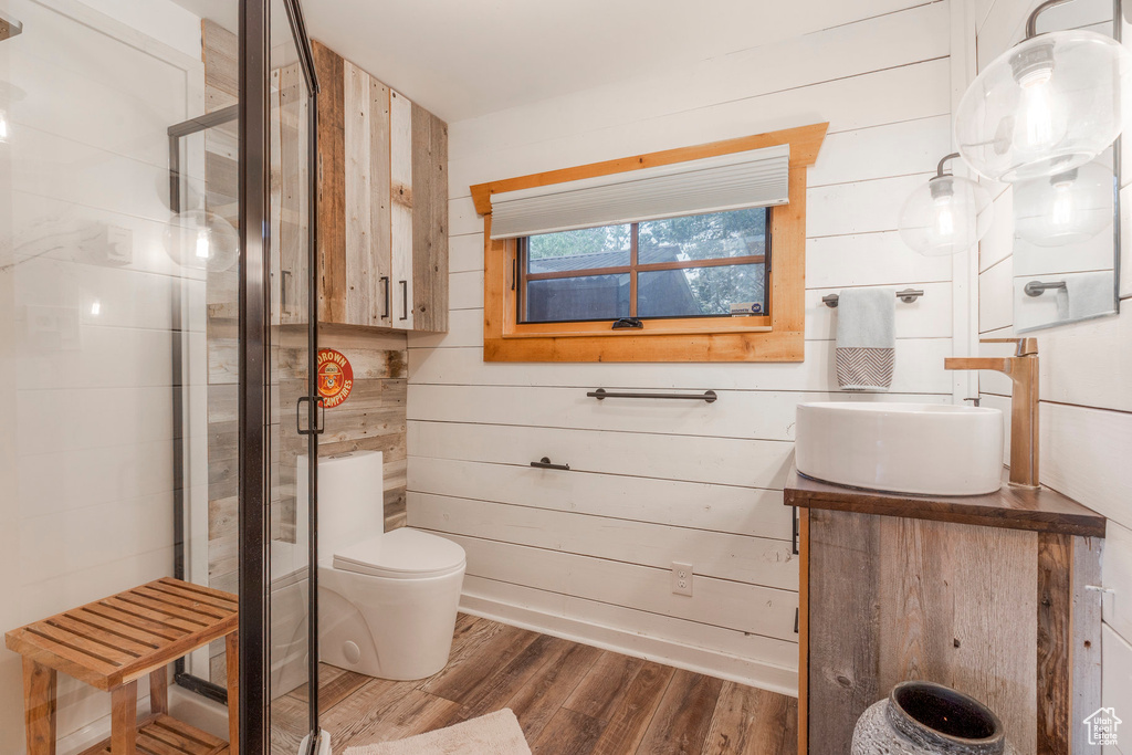 Bathroom featuring wood finished floors, vanity, a stall shower, and wood walls