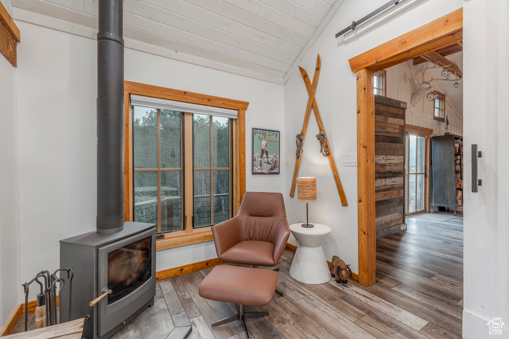 Sitting room with a wood stove, hardwood / wood-style floors, vaulted ceiling, and wood ceiling