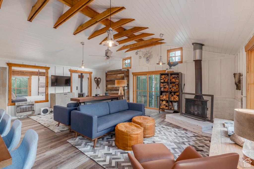 Living room with wood finished floors, healthy amount of natural light, heating unit, a ceiling fan, and beam ceiling