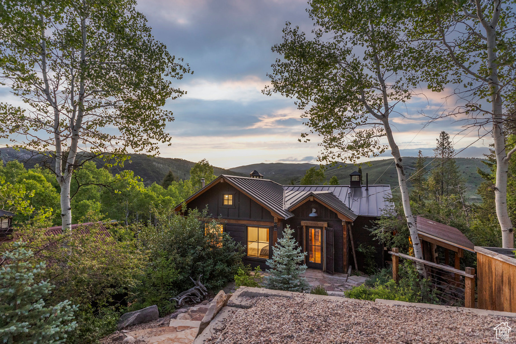 View of front of house featuring board and batten siding, a chimney, a mountain view, a standing seam roof, and a metal roof