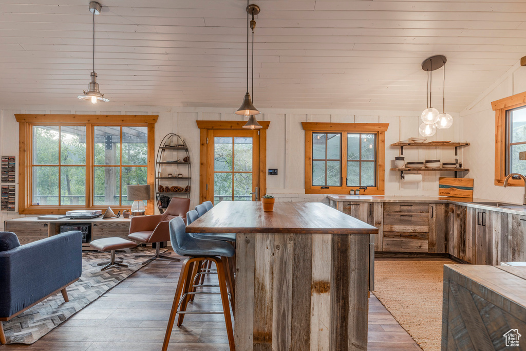 Kitchen featuring hardwood / wood-style floors, open floor plan, lofted ceiling, butcher block countertops, and a center island