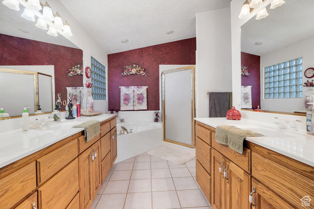 Bathroom with a shower stall, vanity, a garden tub, a textured ceiling, and tile patterned floors