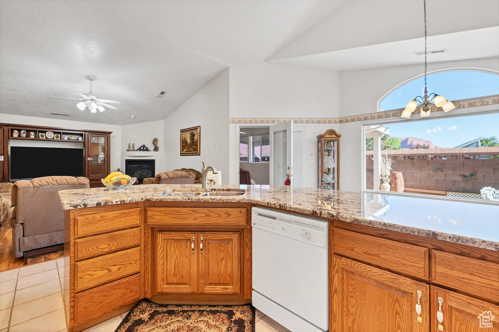 Kitchen with dishwasher, lofted ceiling, open floor plan, a glass covered fireplace, and a ceiling fan