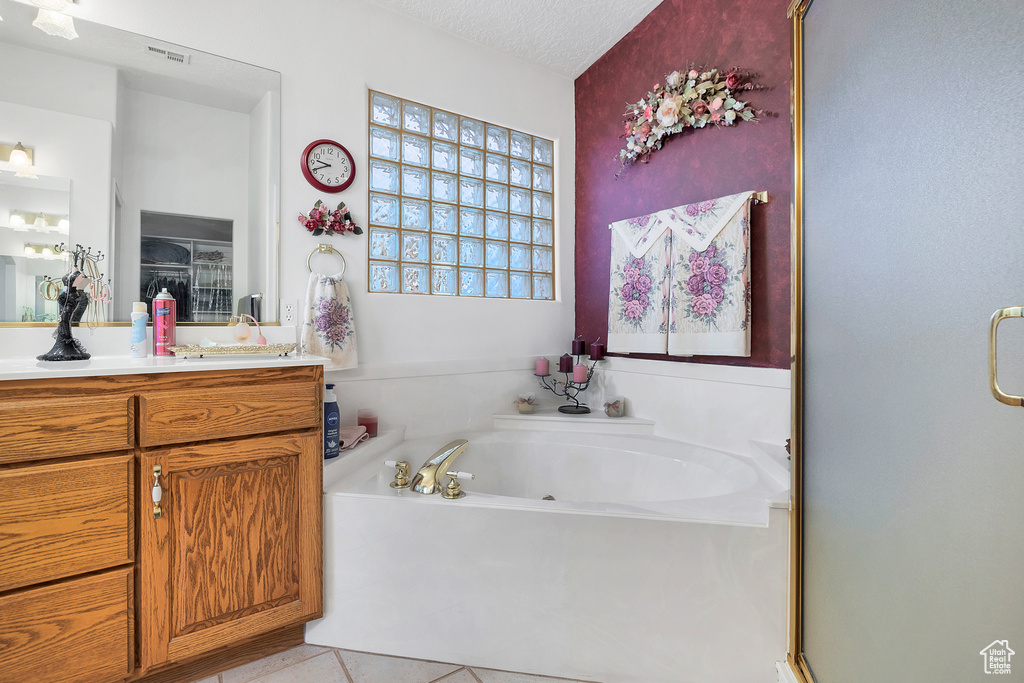 Full bathroom featuring vanity, a garden tub, tile patterned floors, a stall shower, and a textured ceiling