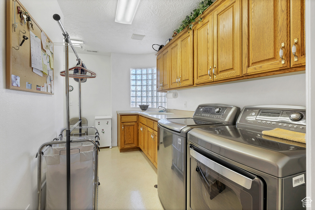 Laundry room with separate washer and dryer, cabinet space, and a textured ceiling