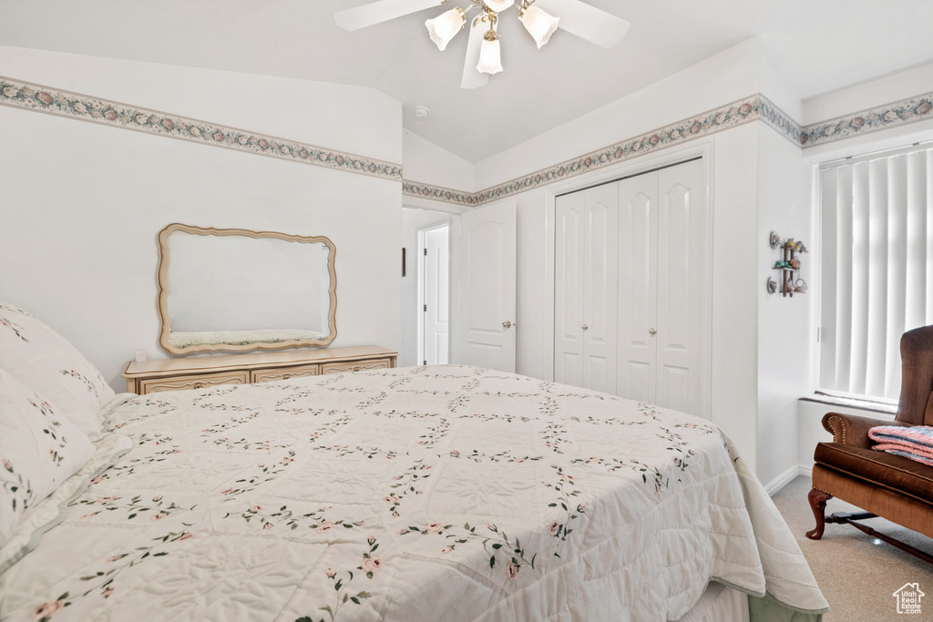 Bedroom featuring light carpet, lofted ceiling, a closet, and a ceiling fan