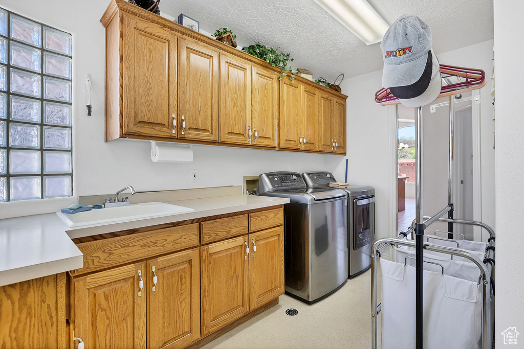 Laundry area with cabinet space, washer and clothes dryer, and a textured ceiling