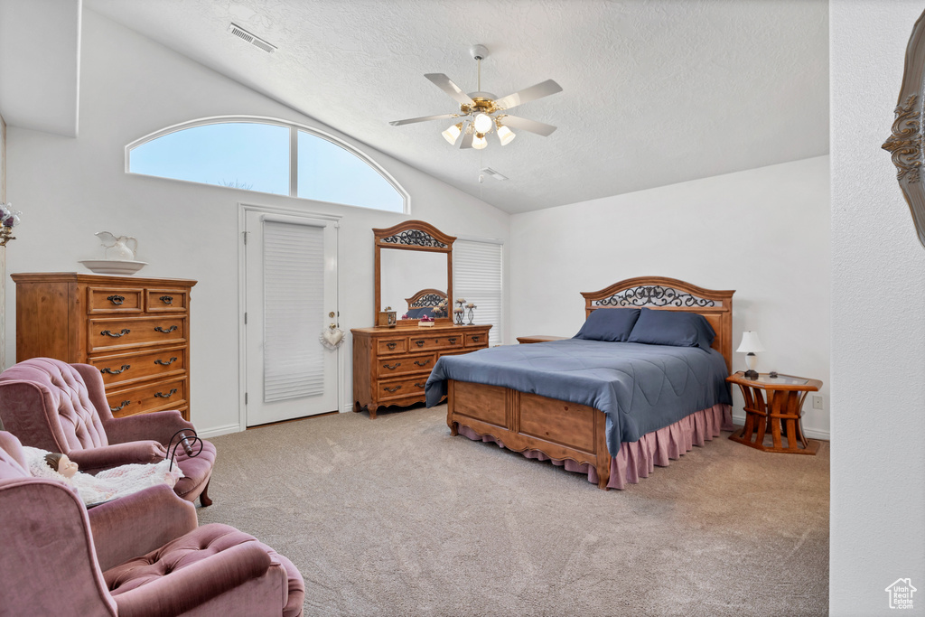 Carpeted bedroom featuring a textured ceiling, vaulted ceiling, and ceiling fan