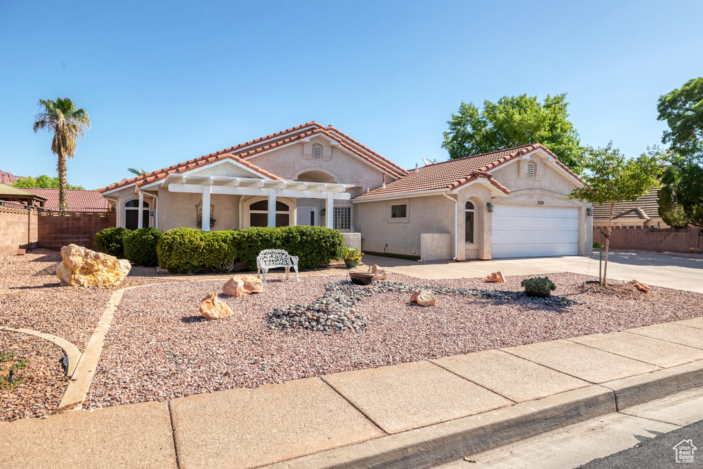 View of front of house with a tiled roof, concrete driveway, stucco siding, an attached garage, and a pergola