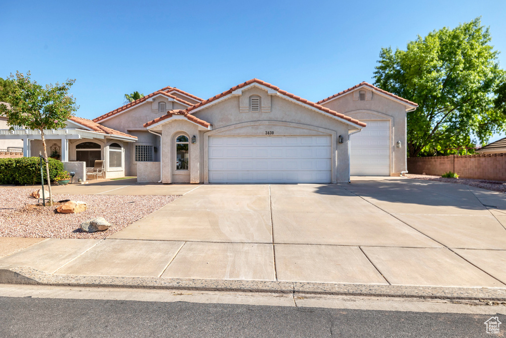 Mediterranean / spanish-style house featuring an attached garage, concrete driveway, a tile roof, and stucco siding