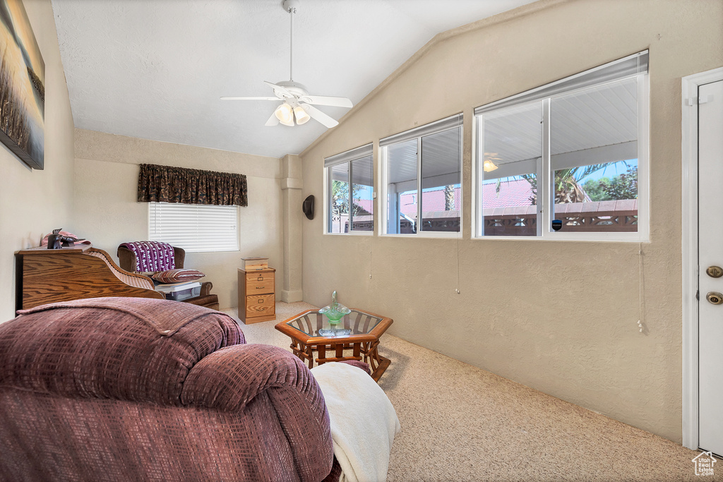 Carpeted living area featuring ceiling fan, healthy amount of natural light, and lofted ceiling