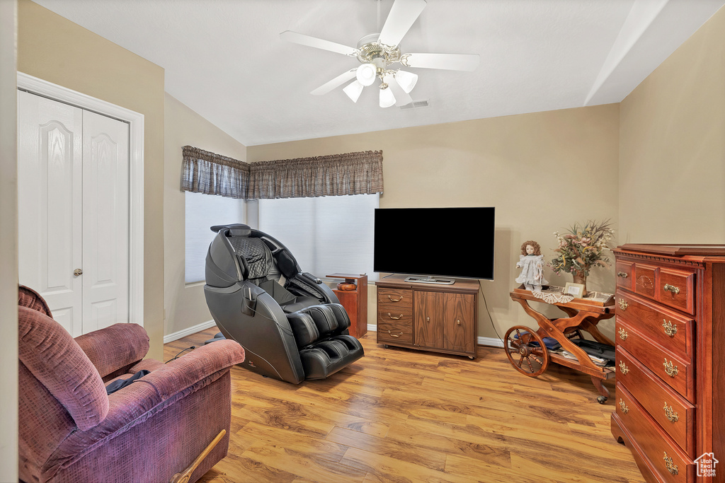Living area with lofted ceiling, a ceiling fan, and light wood finished floors