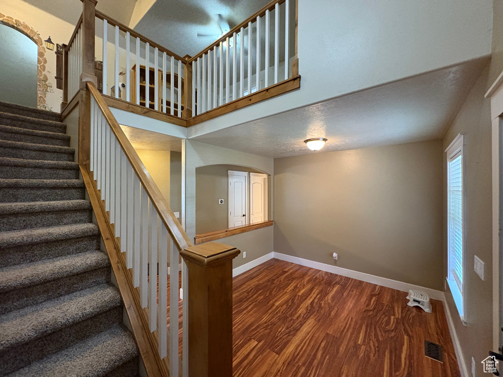 Stairs featuring wood finished floors and arched walkways