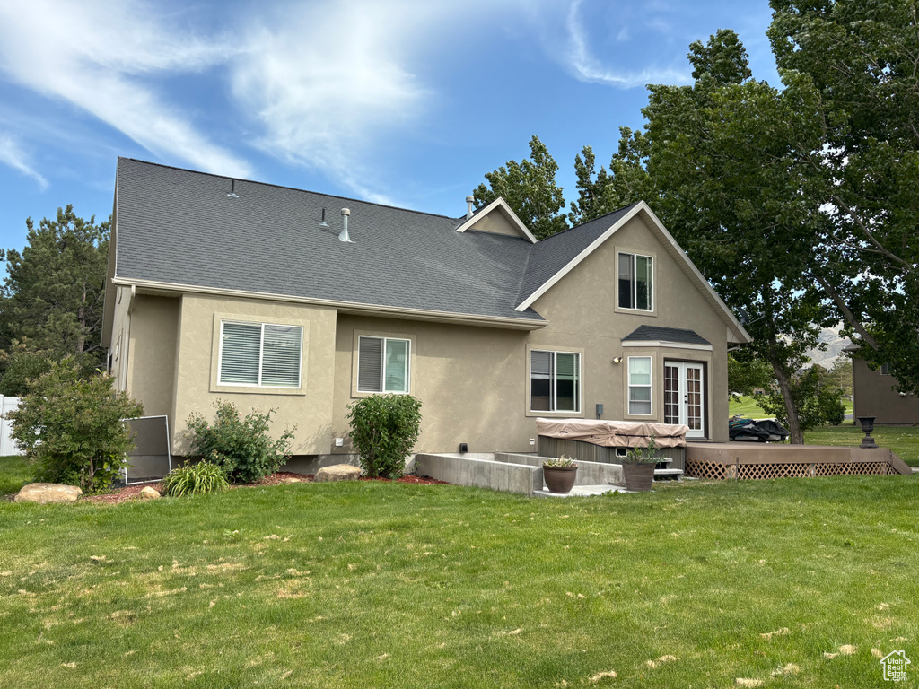 Back of house featuring stucco siding, a lawn, and a shingled roof