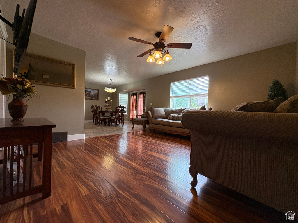 Living room with a textured ceiling, wood finished floors, and ceiling fan