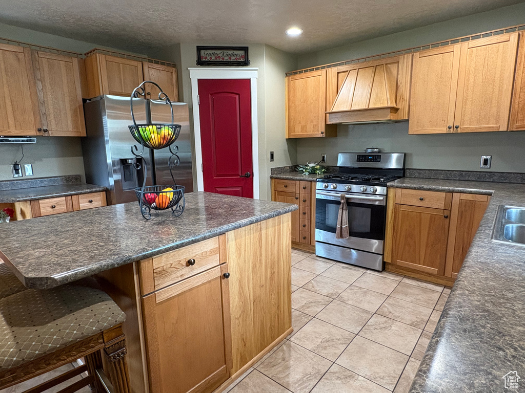Kitchen with custom range hood, stainless steel appliances, dark countertops, a breakfast bar, and recessed lighting