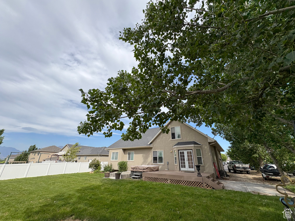 Back of property with stucco siding, a wooden deck, and french doors
