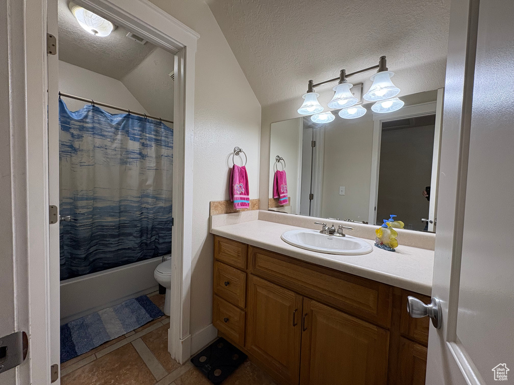 Bathroom with vaulted ceiling, vanity, tile patterned floors, a textured ceiling, and shower / bath combination with curtain