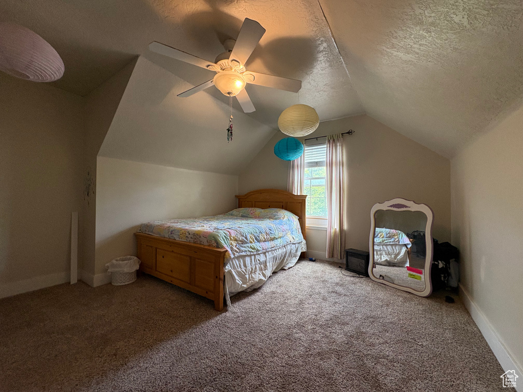 Carpeted bedroom featuring lofted ceiling, a ceiling fan, and a textured ceiling