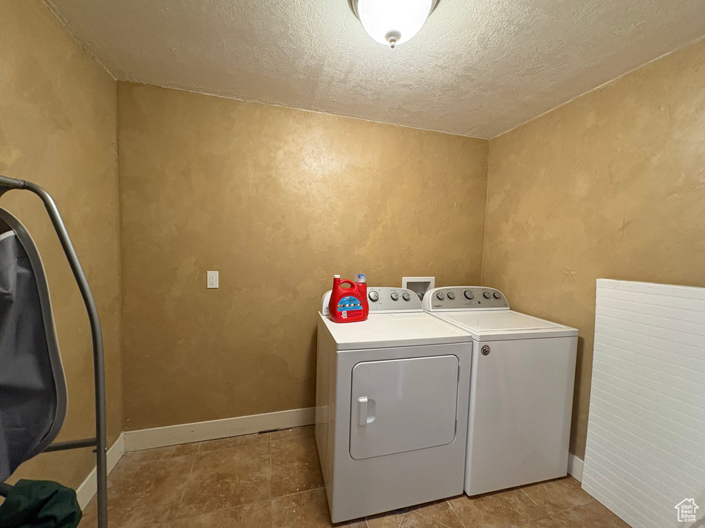 Washroom featuring independent washer and dryer, a textured ceiling, and a textured wall