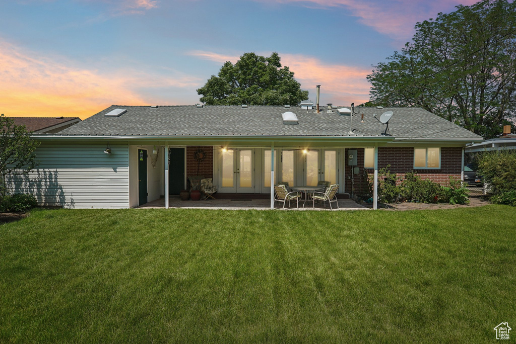 Rear view of house with french doors, a patio area, a lawn, and brick siding