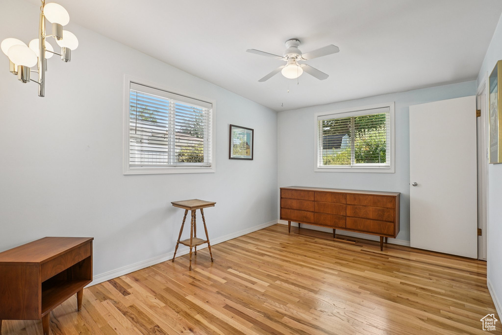 Unfurnished room featuring light wood-style floors, ceiling fan, and a chandelier
