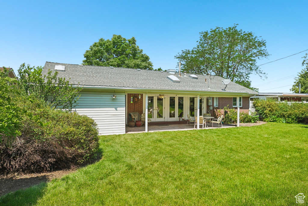 Back of house with french doors, a patio area, and a lawn
