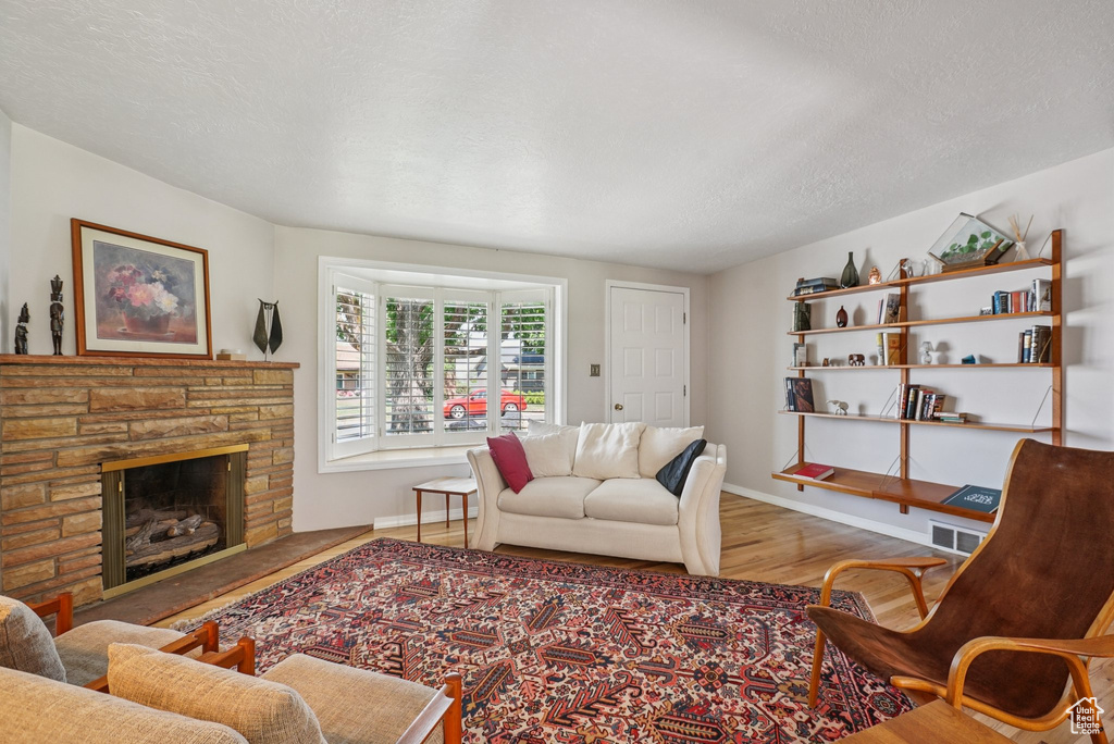 Living area with wood finished floors, a fireplace, and a textured ceiling