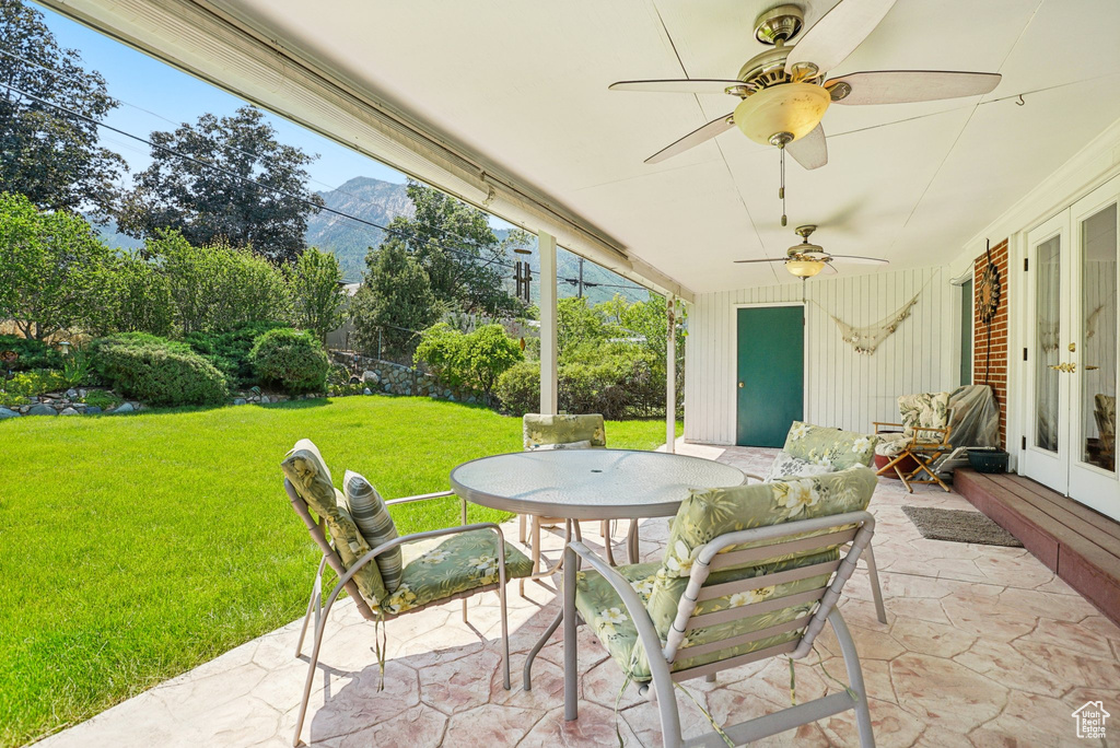 View of patio featuring french doors, a mountain view, outdoor dining space, and ceiling fan