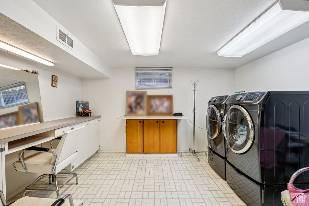 Laundry room featuring washer and dryer, brick patterned floors, and a desk