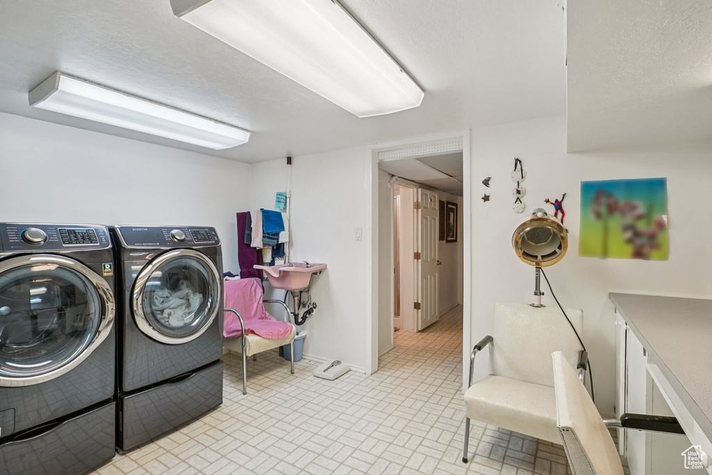 Laundry area with washer and clothes dryer and brick patterned flooring
