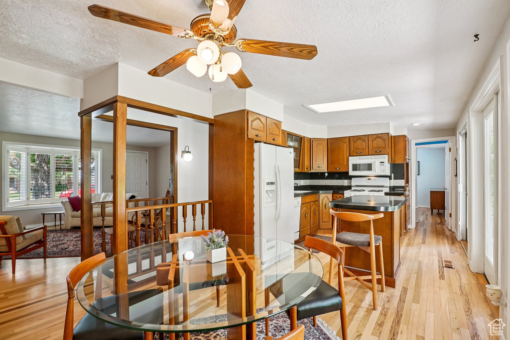 Dining room featuring light wood-style flooring, a textured ceiling, and ceiling fan