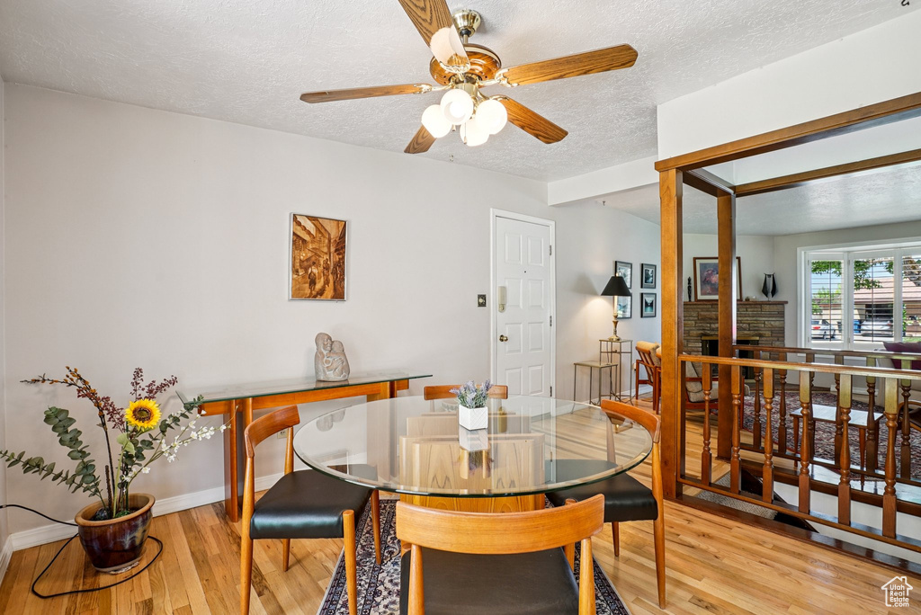 Dining area with light wood-style floors, a textured ceiling, and ceiling fan