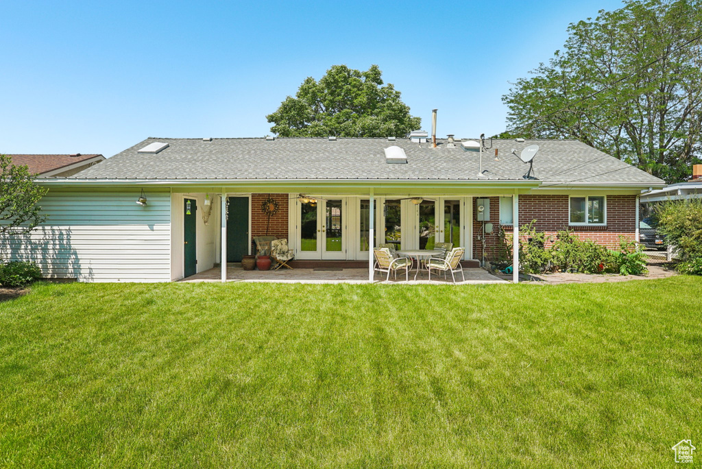 Rear view of house with french doors, a lawn, a patio area, and brick siding