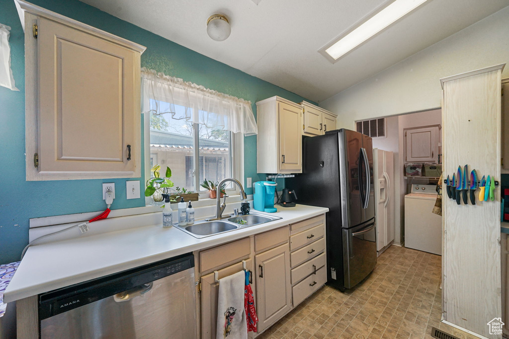Kitchen featuring appliances with stainless steel finishes, washer / clothes dryer, lofted ceiling, light countertops, and brick patterned flooring
