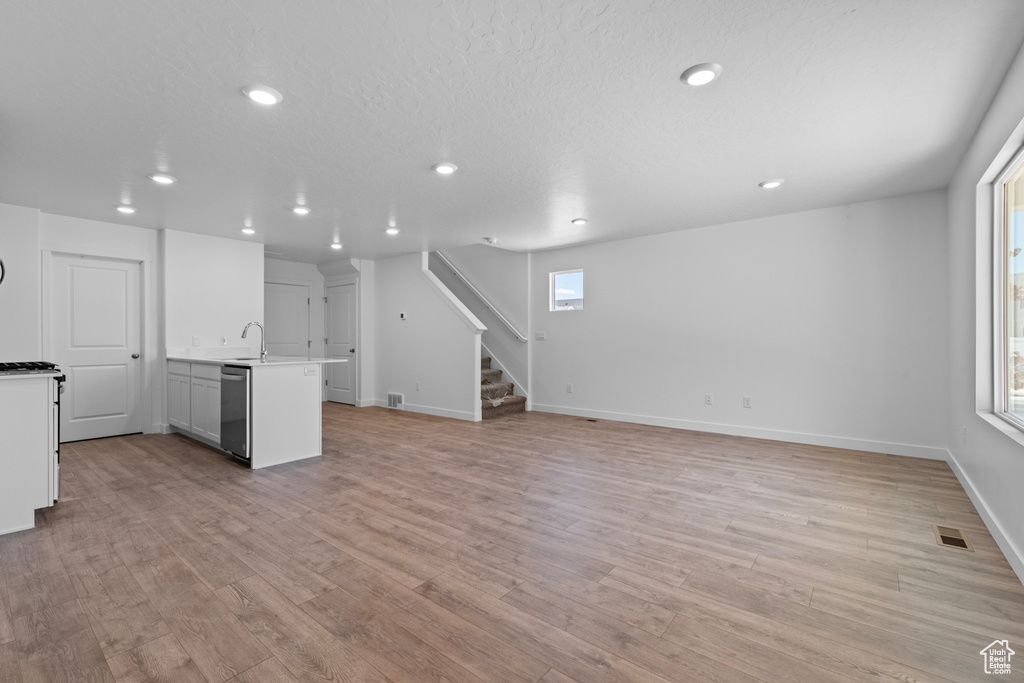 Unfurnished living room with recessed lighting, stairway, and light wood-style floors