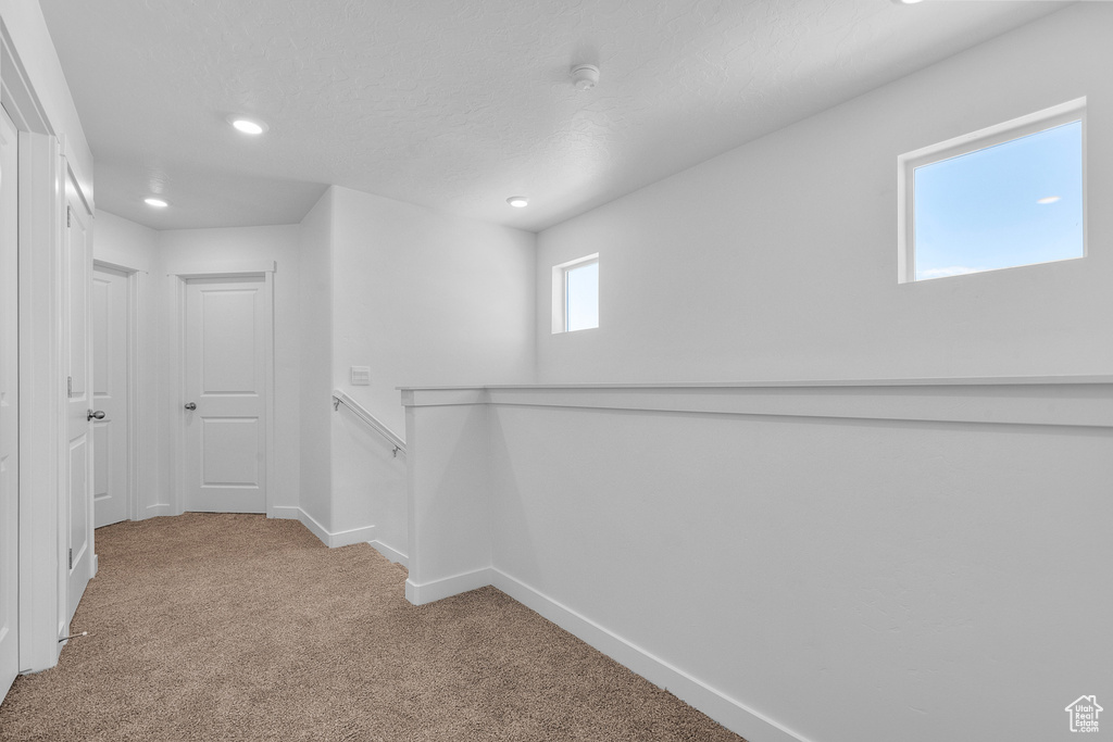 Hallway with carpet, recessed lighting, and an upstairs landing
