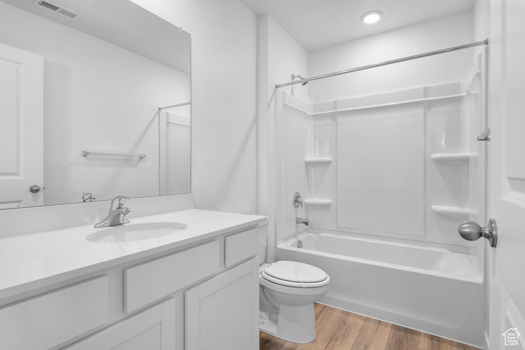 Bathroom with vanity, shower / bath combination, wood finished floors, and recessed lighting