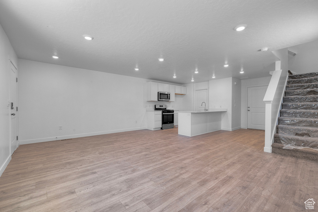 Unfurnished living room featuring recessed lighting, stairway, and light wood-type flooring