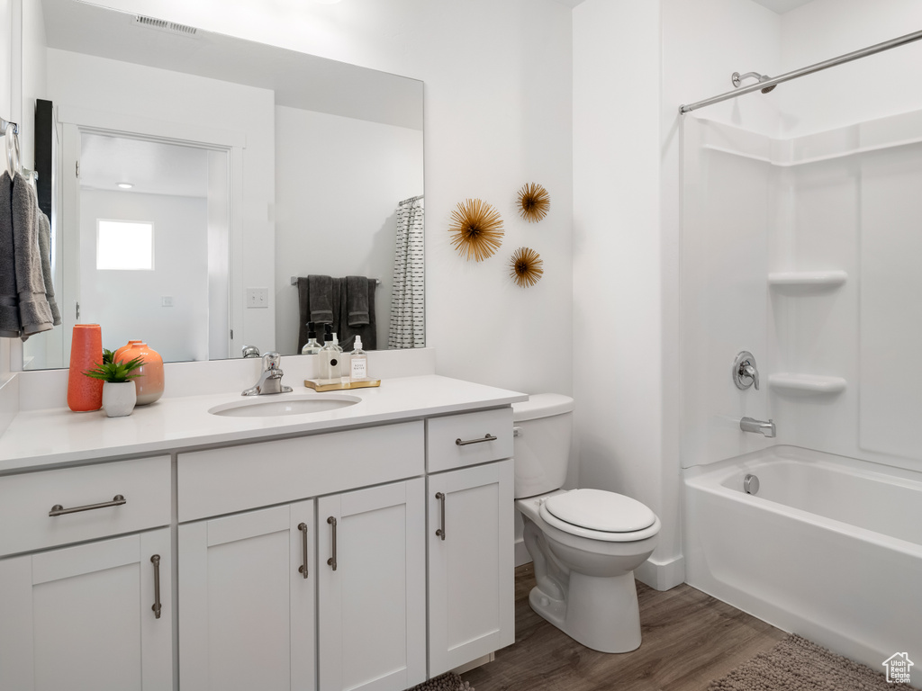 Bathroom with wood finished floors, vanity, and shower / tub combination