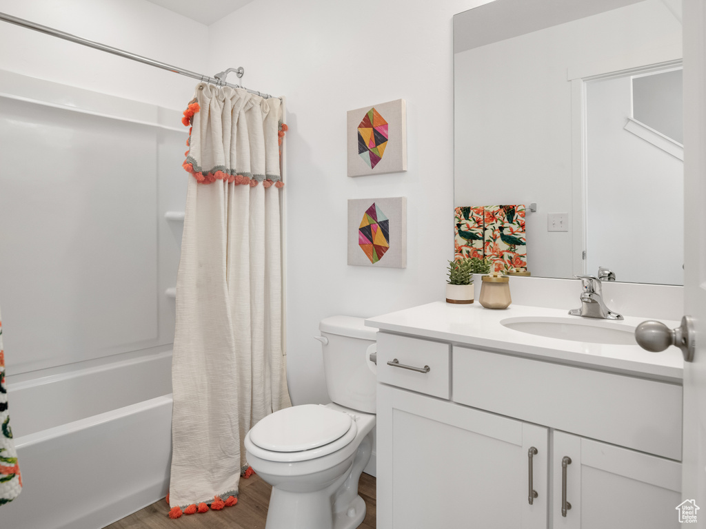 Full bath with wood finished floors, vanity, and shower / bath combination with curtain
