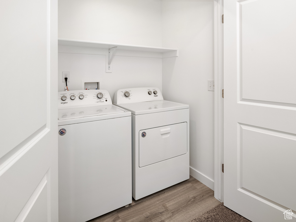 Laundry area with independent washer and dryer and light wood-style floors