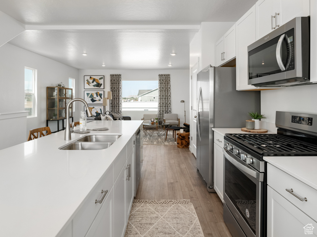 Kitchen with appliances with stainless steel finishes, light wood-style flooring, light countertops, white cabinetry, and recessed lighting