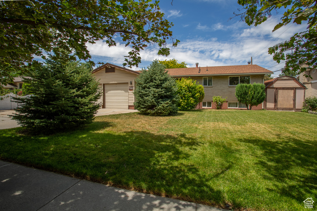 View of front of house featuring a front lawn, an outdoor structure, and concrete driveway