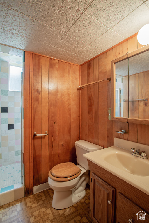 Full bath featuring a shower stall, vanity, and wooden walls